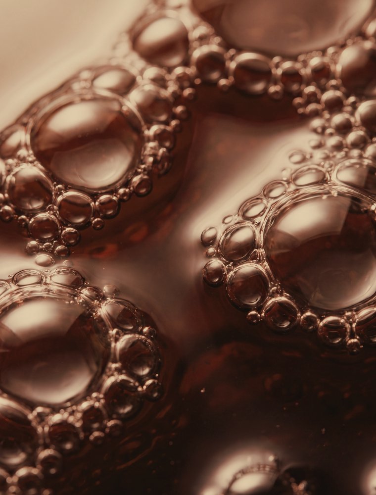 Macro de bolhas em líquido vermelho-terracota, como sangue visto de perto